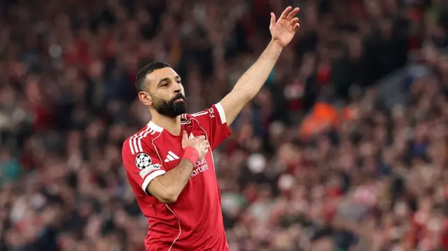 Mohamed Salah points to the Liverpool badge after scoring