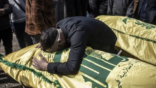 man bent over a coffin draped in yellow silk