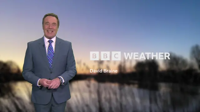 BBC Weather's David Braine in a suit next to a graphic with his name