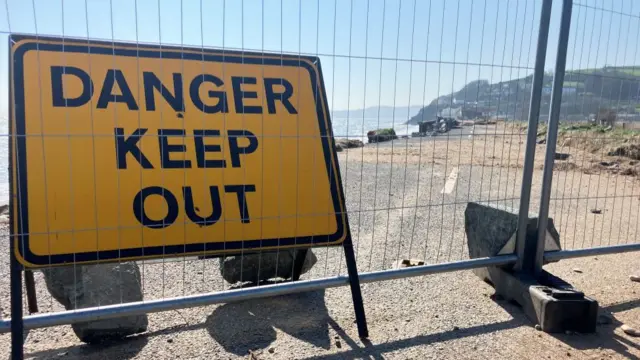 Metal fencing and a "danger keep out" sign on the A379 in Torcross