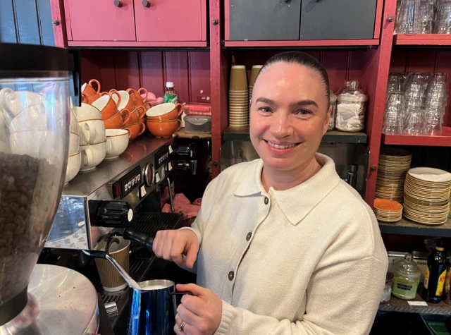 Sophie Treasaden smiles while using a coffee machine