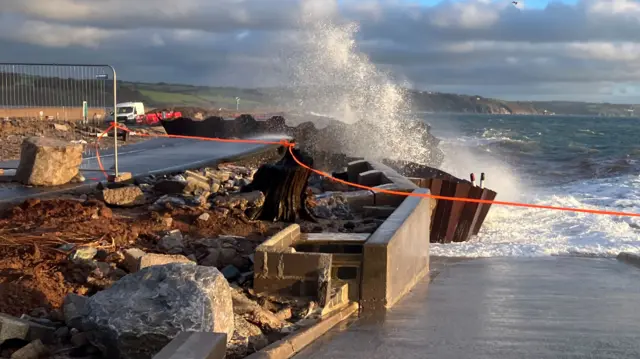 A wave crashes in from the sea on the partially collapsed A379 in Torcross