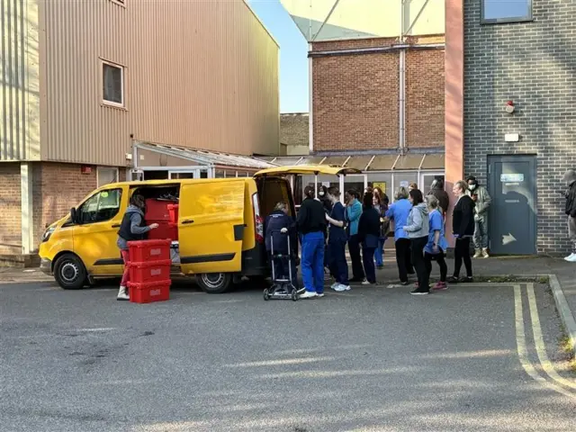 Healthcare workers lining up behind bright yellow van