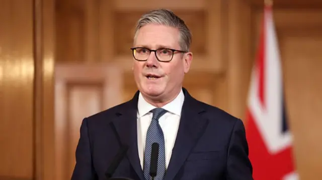 Keir Starmer in dark blue suit delivers speech from room in Downing Street