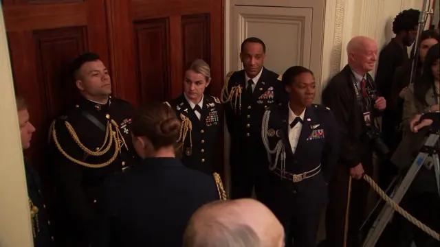 People in military outfits stood in a room.