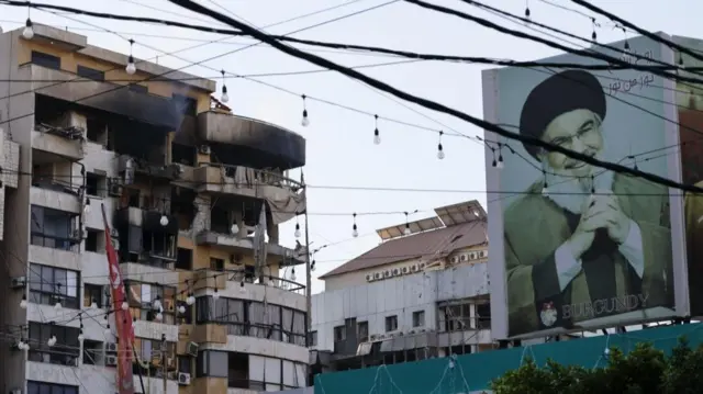 A billboard with a photo of late Hezbollah leader Hassan Nasrallah is seen near a damaged building after an Israeli airstrike in Beirut on Monday