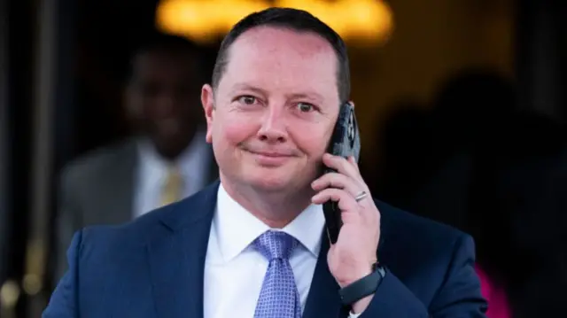 Republican Representative Eric Burlison smiles as he walks and talks on a cell phone