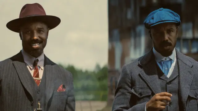 Michael B Jordan as twins, both in suits, one in a peaked, purple hat and one in a blue flat cap