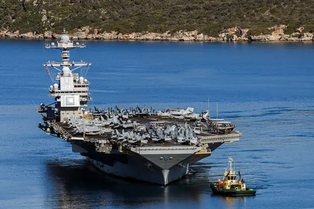 A US aircraft carrier with jets on board in the middle of the sea