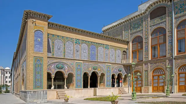 A building covered in intricate tiling and colourful mosaics is seen against a clear blue sky.
