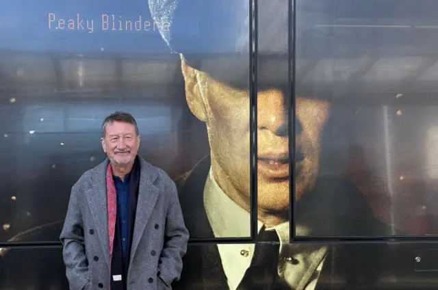 Steven Knight stands in front of a picture of Cillian Murphy