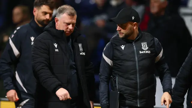 Stoke coach Mark Robins talks to a member of his coaching staff