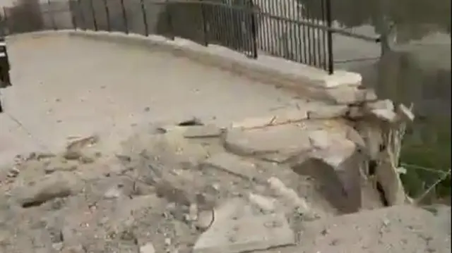 A screengrab from the verified video showing a hole in the pavement and damage to railings from the apparent missile debris