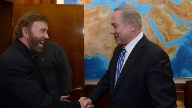 Norris and Netanyahu shaking hands and smiling big in front of a world map