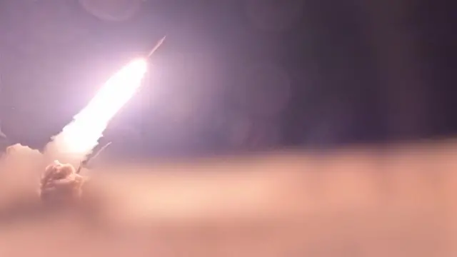 Missile being fired into the air at night, with a trail of smoke behind it