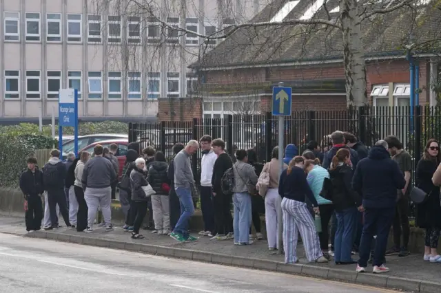 Close up shot as people wait in line outside a meningitis vaccination hub at the Vicarage Lane Clinic in Ashford, Kent.
