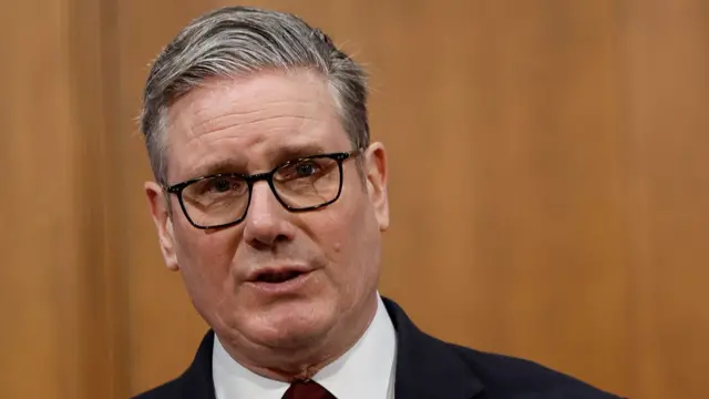 Keir Starmer in front of a wooden wall