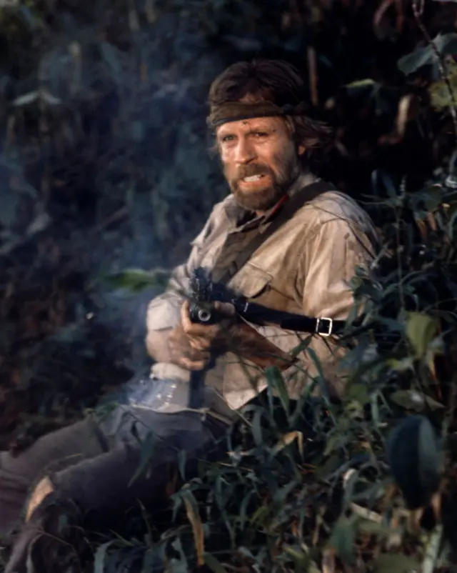 Norris in a jungle shooting a machine gun