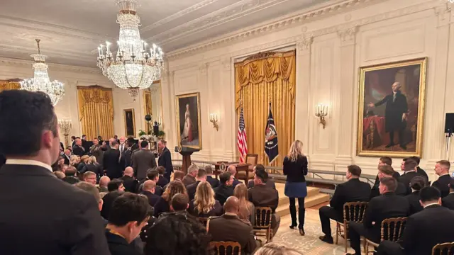 A view from inside the White House East Room where a crowd waits around a lectern where Trump is due to speak