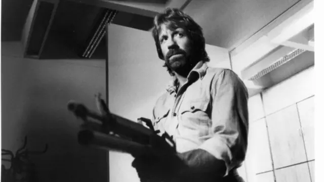 Chuck Norris heavily armed and looking for his ememies in a scene from the film 'Invasion USA', 1985