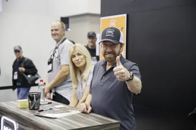 Norris gives thumbs up at stall at convention