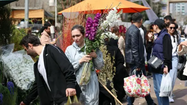Shoppers are seen carrying bunches of flowers and looking at market stalls