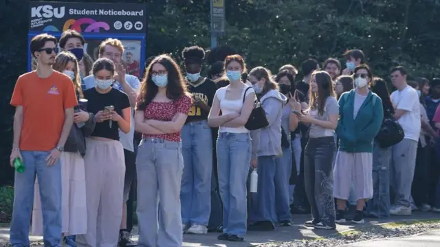 Students queuing to receive vaccines and antibiotics at the University of Kent campus in Canterbury. A number are wearing masks. Students receiving vaccines and antibiotics from medical staff in the sports hall at the University of Kent campus in Canterbury