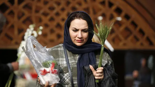 A woman carries plants in preparation for Nowruz.