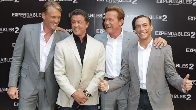 four action stars lined up in front of a step-and-repeat for Expendables 2