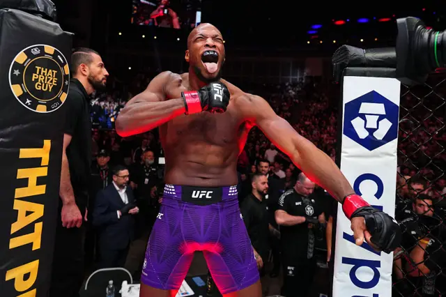 Michael Page in purple shorts enters the octagon with his tongue out