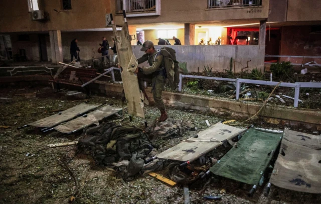 An Israeli soldier prepares stretchers at the impact site after Iranian missile barrages struck residential buildings in Arad