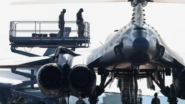Two members of ground crew stand on a scissor lift by a USAF B-1B bomber at RAF Fairford airbase