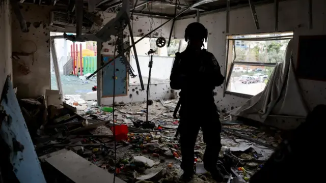 A member of the Israeli security personnel stands inside damaged kindergarten at an impact site, following a barrage of missiles launched from Iran