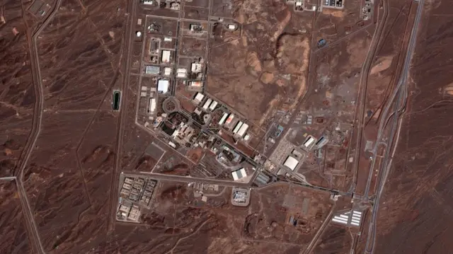 A satellite image shows a birds eye view of a nuclear facility and includes dozens of buildings amidst red rock