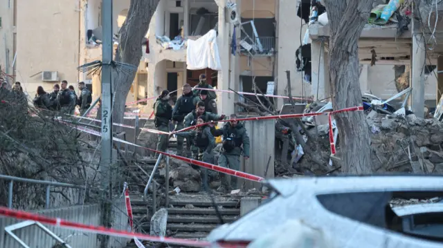 Israeli security, rescue, and paramedics work at at the scene of a direct hit of an Iranian missile in Arad, Israel, 22 March 2026.