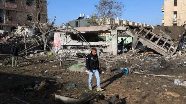 A man walks near a destroyed building following a night of Iranian missile strikes which injured dozens of Israelis.