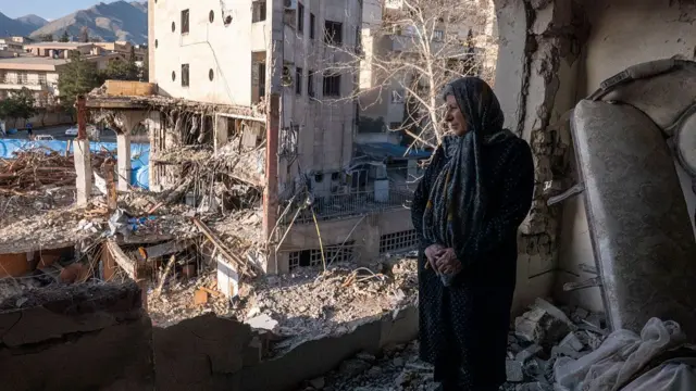 A woman looks out from her destroyed apartment in the remains of a residential and commercial building in the Shahrak-e Gharb neighbourhood of Tehran, Iran.