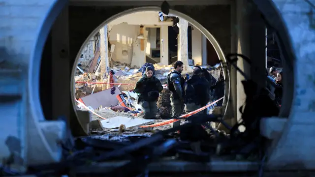 Security personnel work at the site of damage after Iranian missile barrages struck residential buildings