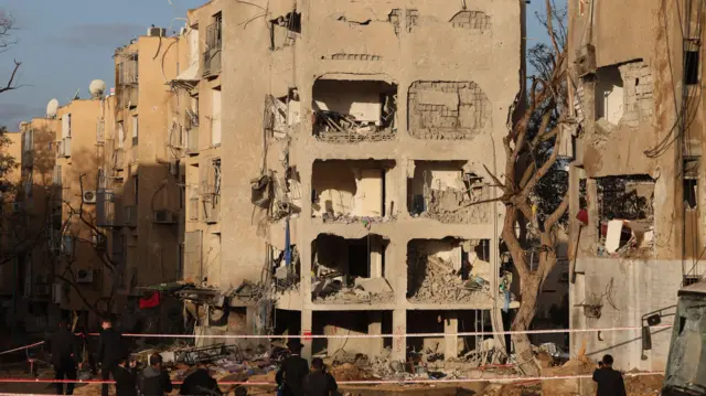 People look on at the scene of a direct hit of an Iranian missile in Arad, Israel, 22 March 2026.