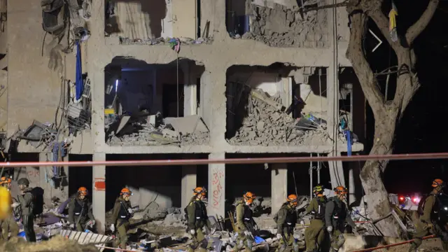 Israeli soldiers work at the scene of damage after Iranian missile barrages struck residential buildings in Arad.
