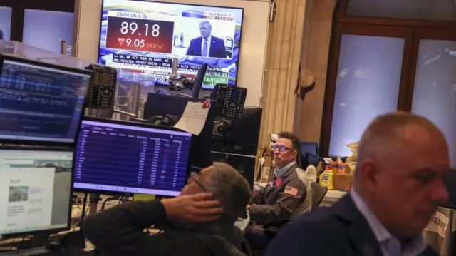 A TV screen shows live footage of US President Donald Trump speaking as traders work on the floor of the New York Stock Exchange (NYSE) after the opening bell in New York, New York, USA, 23 March 2026.