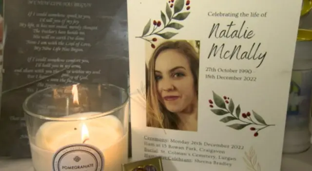 A memorial card with Natalie McNally's picture on it and a candle to the left of it.