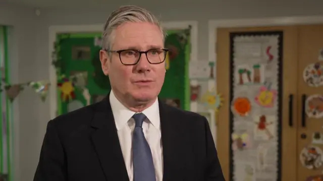Keir Starmer in a suit and glasses in a school setting