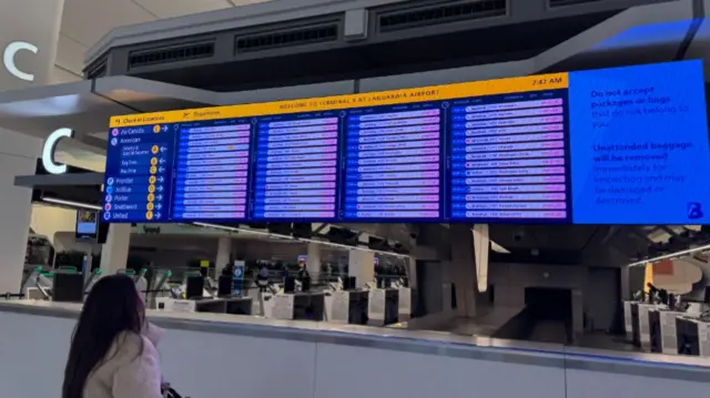 A woman looking at a board at LaGuardia Airport.