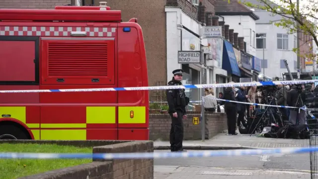 A police officer is seen beside a fire engine behind at police cordon at the scene in Highfield Road, Golders Green, London, after an apparent arson attack on four ambulances belonging to the Jewish Community Ambulance service in London.