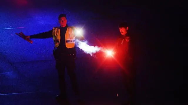 A man in a high-vis jacket redirects traffic