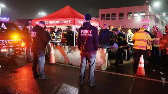 Two FDNY staff stand by an emergency response tent sent up on the tarmac