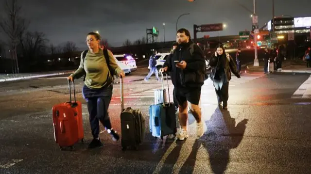 Two passengers walk with suitcases along the tarmac