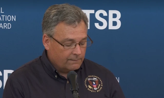 A man in glasses speaks into a microphone