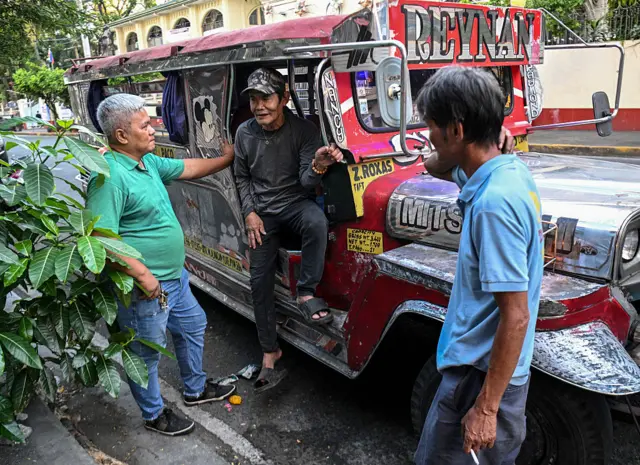 A jeepney driver speaks with fellow drivers at a terminal in Manila